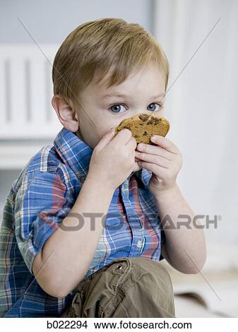 Picture - little boy eating a cookie. Fotosearch