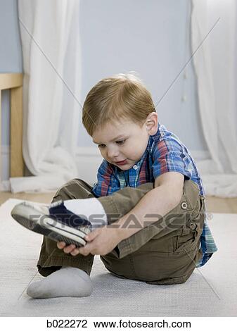 Stock Image - little boy putting on shoes. Fotosearch