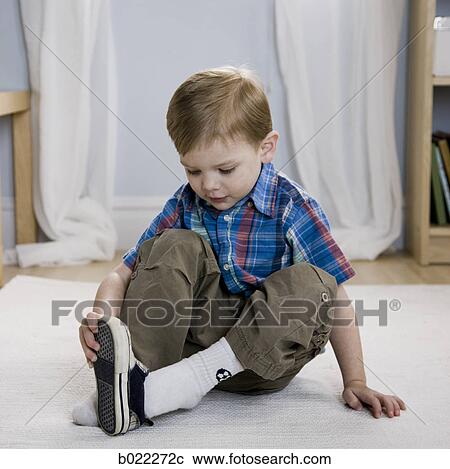 Stock Image - little boy putting on shoes. Fotosearch