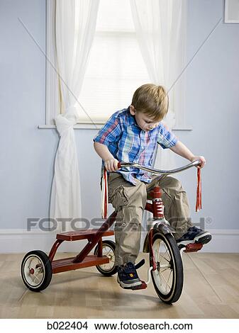 Picture - little boy riding a tricycle. Fotosearch