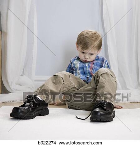 Picture - little boy wearing a man's shoes. Fotosearch