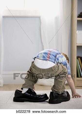 Stock Photo - little boy wearing a man's shoes. Fotosearch