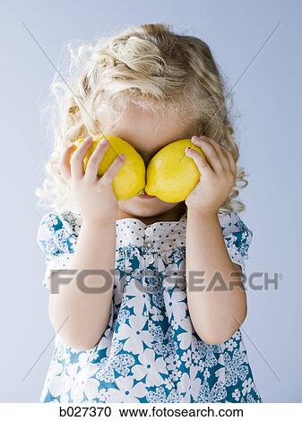 little girl holding lemons in front of her eyes View Large Photo Image Stock Image - little girl holding lemons in front of her eyes. Fotosearch