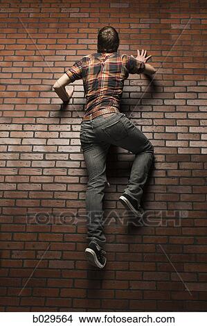 man climbing up a brick wall View Large Photo Image Picture - man climbing up a brick wall. Fotosearch
