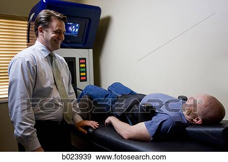 Stock Photo - man getting treatment on a chiropractic machine. Fotosearch