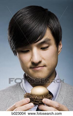 man holding a golden egg in a nest View Large Photo Image Picture - man holding a golden egg in a nest. Fotosearch