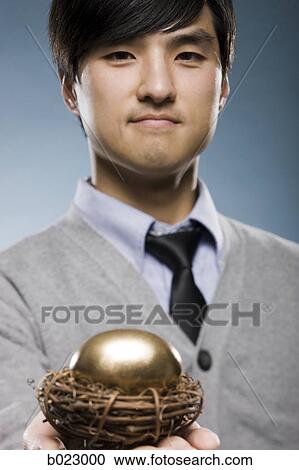 man holding a golden egg in a nest View Large Photo Image Stock Image - man holding a golden egg in a nest. Fotosearch