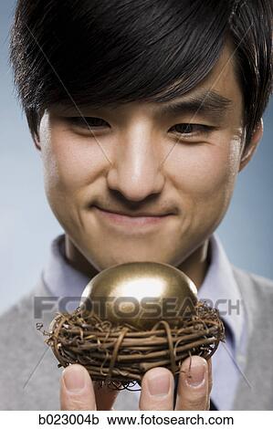 man holding a golden egg in a nest View Large Photo Image Stock Image - man holding a golden egg in a nest. Fotosearch