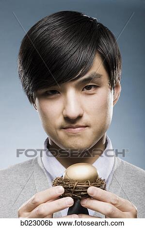 man holding a golden egg in a nest View Large Photo Image Stock Image - man holding a golden egg in a nest. Fotosearch