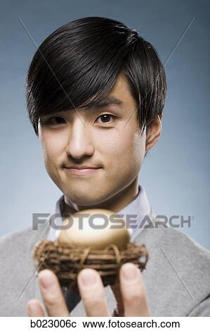 man holding a golden egg in a nest View Large Photo Image Stock Image - man holding a golden egg in a nest. Fotosearch