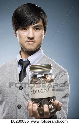 Stock Image - man holding a jar of coins. Fotosearch
