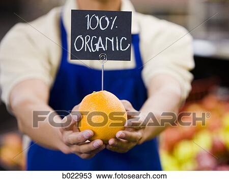 Stock Image - man holding an organic orange. Fotosearch