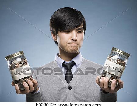 Stock Image - man holding two jars of coins. Fotosearch