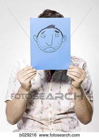 man holding up a frowny face drawing View Large Photo Image Stock Photograph - man holding up a frowny face drawing. Fotosearch