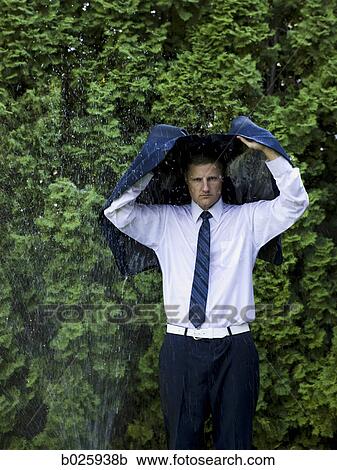 Stock Image - man in a suit standing next to a sprinkler. Fotosearch