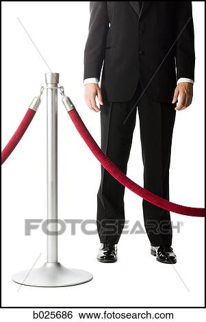 Stock Photograph - man in a tuxedo next to a velvet rope. Fotosearch