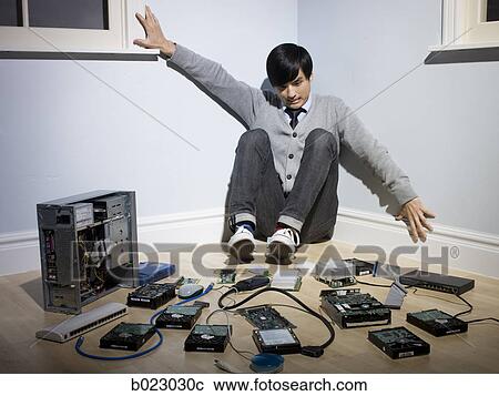 Stock Image - man in the corner surrounded by computer parts. Fotosearch