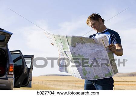 Picture - man looking at a map on the side of the road. Fotosearch