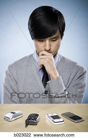 Stock Image - man looking at cell phones. Fotosearch