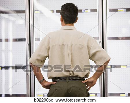 man looking into empty refrigerators at market View Large Photo Image Stock Image - man looking into empty refrigerators at market. Fotosearch