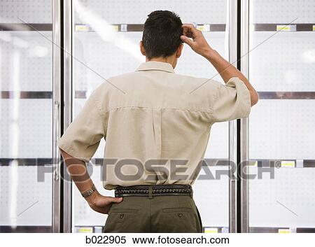 Stock Photography - man looking into empty refrigerators at market. Fotosearch