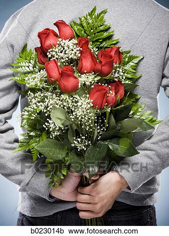 Stock Image - man with flowers behind his back. Fotosearch