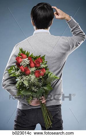 Stock Image - man with flowers behind his back. Fotosearch