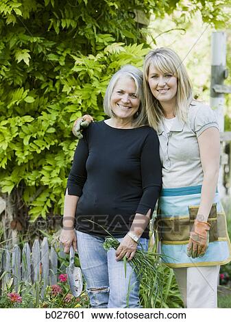 Stock Image - mother and adult daughter in the garden together. Fotosearch