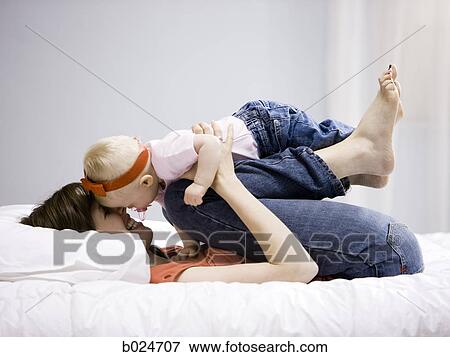 Stock Photo - mother and baby girl lying on a bed. Fotosearch