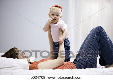 mother and baby girl lying on a bed View Large Photo Image Stock Photo - mother and baby girl lying on a bed. Fotosearch