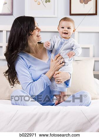 Stock Image - mother and baby on a bed. Fotosearch