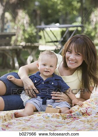 Stock Photograph - mother and baby son in the garden on a blanket. Fotosearch