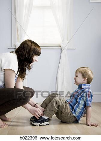 Stock Photograph - mother dressing her son. Fotosearch