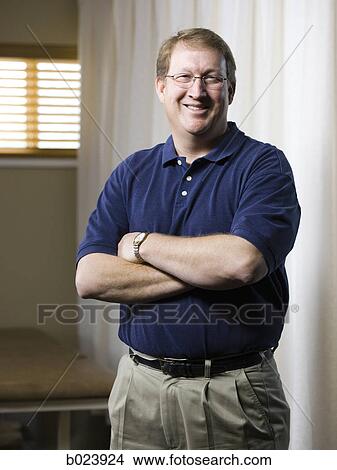 Picture - physical therapist standing with arms folded. Fotosearch