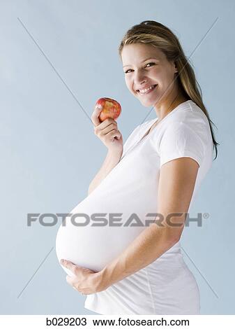 Stock Image - pregnant woman eating an apple. Fotosearch