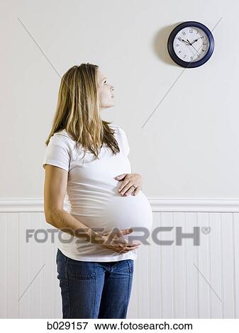 pregnant woman looking at a clock View Large Photo Image Stock Photo - pregnant woman looking at a clock. Fotosearch