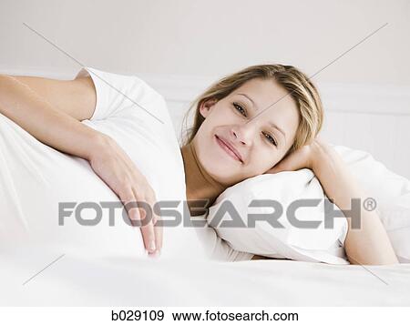 Stock Photo - pregnant woman lying in bed on her side. Fotosearch