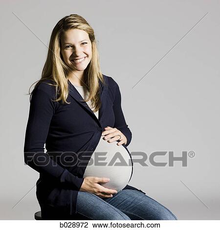 Stock Image - pregnant woman touching her belly. Fotosearch
