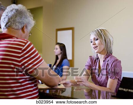 receptionist talking to patients at a doctor's office View Large Photo Image Picture - receptionist talking to patients at a doctor's office. Fotosearch