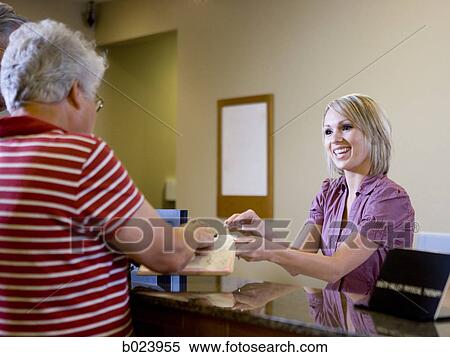 receptionist talking to patients at a doctor's office View Large Photo Image Stock Photography - receptionist talking to patients at a doctor's office. Fotosearch