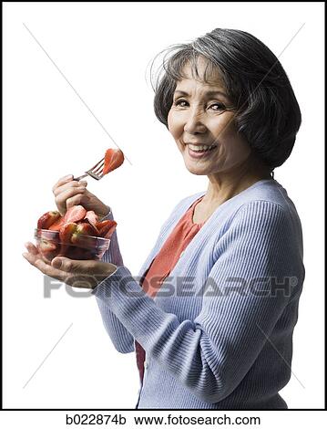 Stock Image - senior woman eating strawberries. Fotosearch