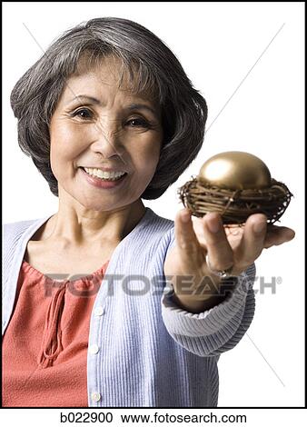 senior woman holding a golden egg View Large Photo Image Stock Image - senior woman holding a golden egg. Fotosearch