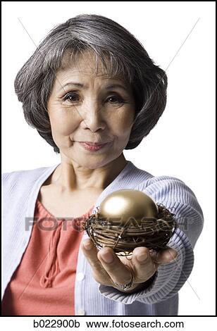 senior woman holding a golden egg View Large Photo Image Stock Image - senior woman holding a golden egg. Fotosearch