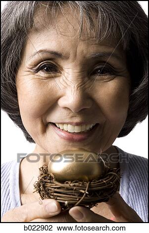 senior woman holding a golden egg View Large Photo Image Stock Image - senior woman holding a golden egg. Fotosearch