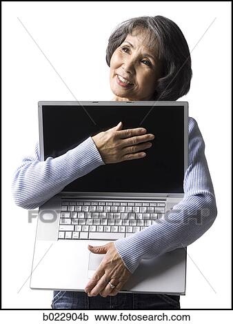 Stock Image - senior woman holding a laptop. Fotosearch