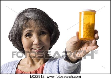 Stock Image - senior woman holding bottle of pills. Fotosearch
