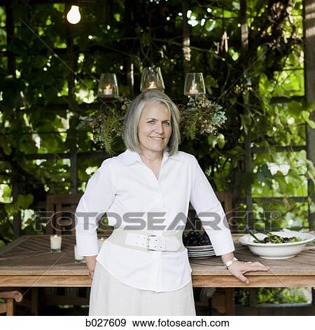 senior woman leaning against a wooden serving table View Large Photo Image Stock Photo - senior woman leaning against a wooden serving table. Fotosearch
