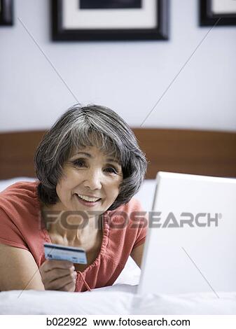 Stock Image - senior woman making an online purchase with her credit card. Fotosearch