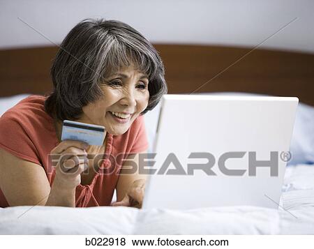 Stock Photo - senior woman making an online purchase with her credit card. Fotosearch