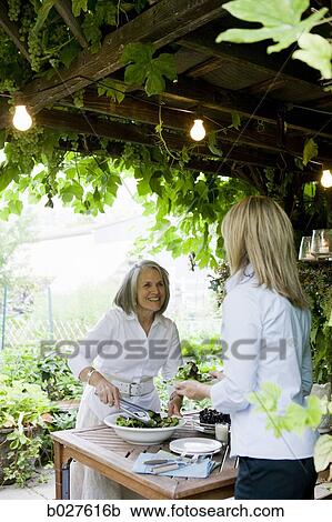 Stock Image - senior woman preparing food outdoors. Fotosearch